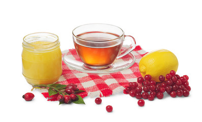 Cup of tea, lemon and honey pot, roze hips and berries of viburnum isolated on white background.