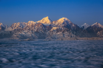 Minya Konka (Mount Gongga) view from Niubeishan Cattle Back Mountain in Sichuan Province, China. Summit shrouded in clouds. Highest Mountain in Sichuan Province China. Twilight moonlit landscape