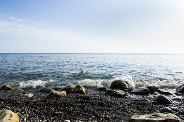 the blue waves crashing against the stones lying on the shore of the black sea and dust flying from them