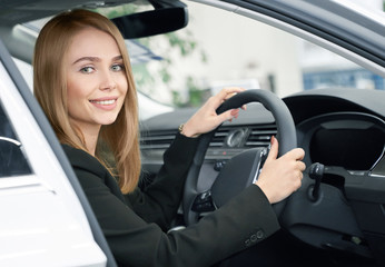 Blonde sitting in new automobile, buyer of car.
