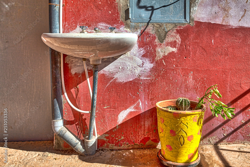 Wall mural a still life with a washbasin and a plant in a bright yellow pot, seen in a restaurant in a mountain