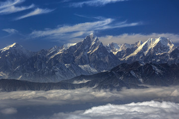Fototapeta na wymiar Edge of the Himalayas - view from Niubeishan Cattle Back Mountain in Sichuan Province, China. View on Clear day above the sea of clouds, blue sky. Himalayan snow capped high altitude mountains