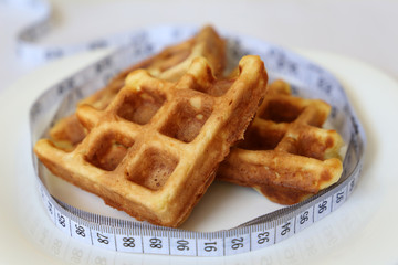 Belgian waffles and measuring type in white plate. Diet and slimming concept, weight loss, healthy breakfast