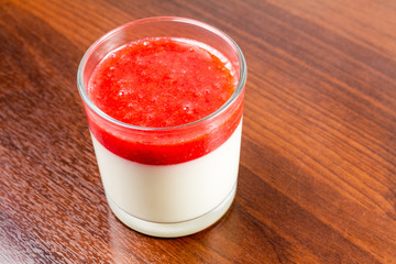Strawberry panna cotta dessert in a glass isolated on a wood table recipe idea 