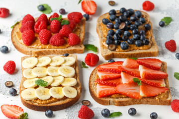 Peanut butter sandwiches with fresh strawberry, blueberry, raspberry and banana whole meal toasts.
