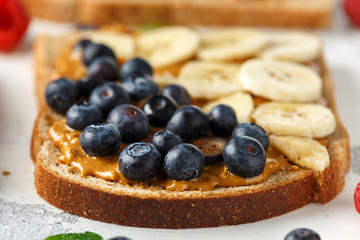 Peanut butter sandwiches with fresh strawberry, blueberry, raspberry and banana whole meal toasts.