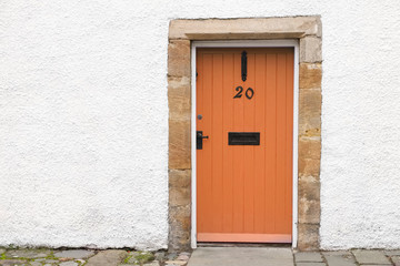 Fototapeta na wymiar Orange old wooden door rustic ancient house entrance in Culross