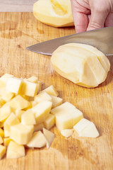 cook cuts potatoes on a wooden board