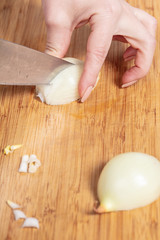 cook cuts onion on a wooden board