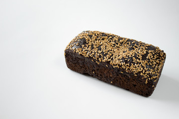 Loaf of rye bread with sesame seeds on white background. Photo with copy blank empty space.