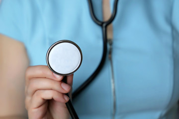 Woman doctor with stethoscope. Girl in blue dress holding a phonendoscope in hand close-up, concept of diagnosis, auscultation, medical exam