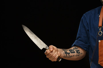 Tattooed man's hand keeping metallic knife.