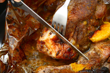 Roasted meat baked in the oven, knife and fork cutting roast.