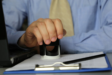 Man in the office puts a stamp on the documents. Concept of official, manager, permission, businessman, contract