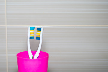 Toothbrushes in a plastic glass close-up. Copy space. Concept: hygiene, family relationships, intimate relationships, understanding, love