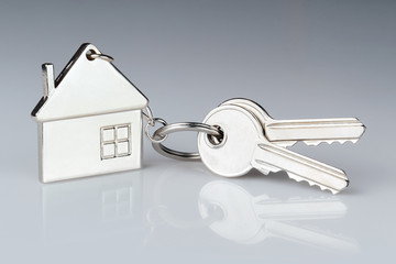 House keys with house shaped keychain on gray background