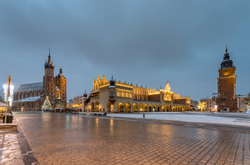 Naklejka premium Krakow, Poland, main market square, winter night, St Mary's church and Cloth Hall illuminated