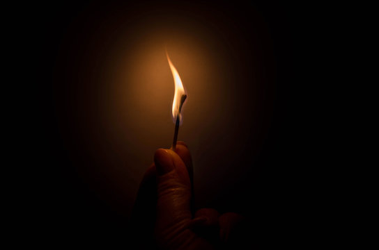 burning match in female hand in the dark
