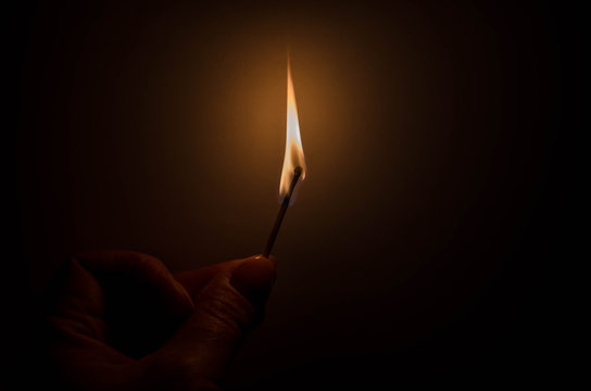 burning match in female hand in the dark
