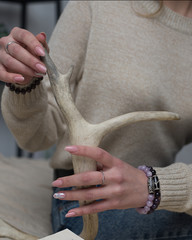 girl with quartz and amethyst bracelets holding a deer antler, a girl with a beautiful manicure holding a deer antler ( close up).