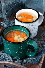 Ceramic cups with vegetable soup on rustic wooden background