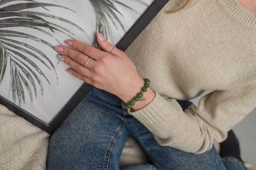 the girl has a jade bracelet, a green bracelet on her arm, a jade bracelet on her arm, a jewel on her arm, a girl is holding a picture with a foliage pattern