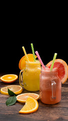 Fototapeta na wymiar Glasses of fruit smoothie with Pink Grapefruit and orange. Dark background.