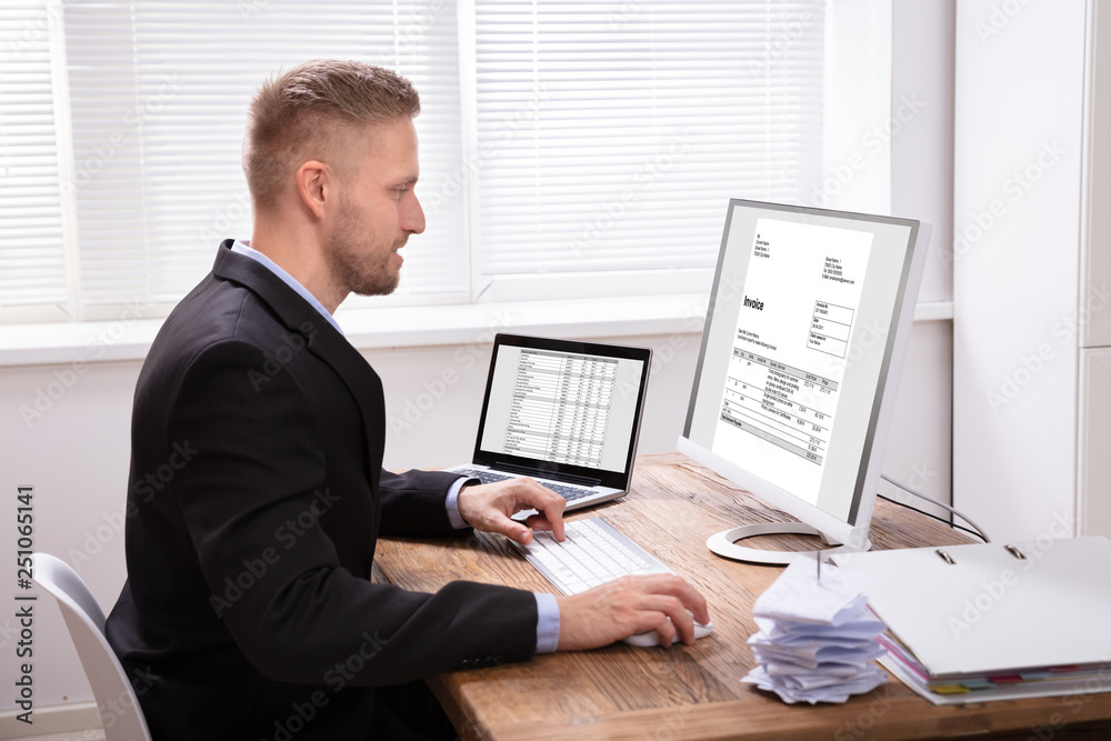 Poster smiling businessman checking invoice on computer