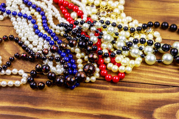 Different beads necklaces on wooden background