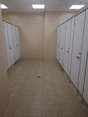 Room corridor with white doors in the cabins. Toilet in the mall. Public toilet in office