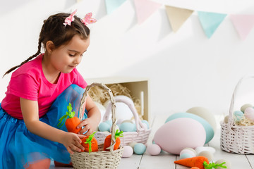 Cute little child girl wearing bunny ears on Easter day. Girl holding basket with painted eggs.