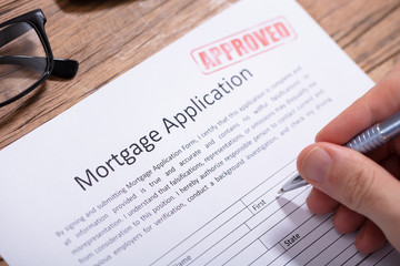 Person's Hand Holding Pen On Mortgage Application