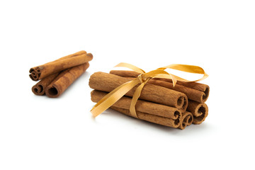 Cinnamon sticks wrapped with golden tape isolated on white background.