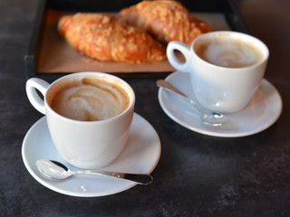 two cup of coffee with freshly baked croissants
