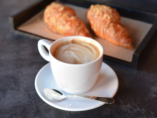 cup of coffee with freshly baked croissants