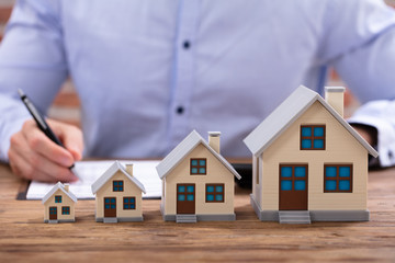 Businessman Calculating Invoice With House Model