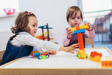 Children toddlers girls play toys at home, kindergarten or nursery.