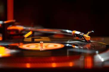 Professional party dj plays music with turntable in night club