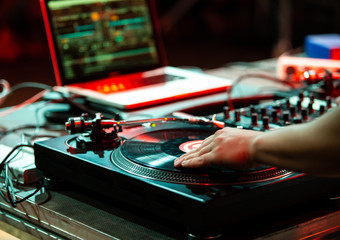 Professional party dj plays music with turntable in night club