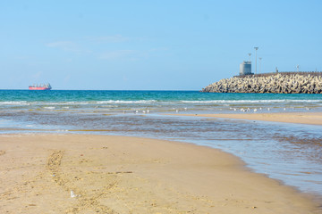 Fototapeta na wymiar Stone breakwater, sandy beach, blue sea. Ashdod, Israel