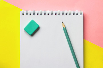 Notepad on yellow and pink background and pencil and eraser