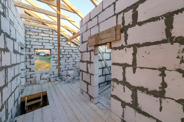 House interior under construction and renovation. Energy saving walls of hollow foam insulation blocks and bricks, ceiling beams and roof frame.