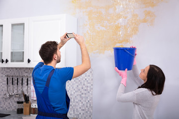 Repairman Taking Photo On Mobilephone Of Water Damage