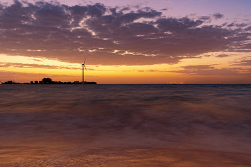 Renewable energy with wind turbines at the sea in sunset