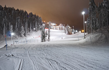 Kuusamo / Finland: View from the illuminated Talvijarvi slope to the upper lifts and slopes in the Ruka ski area on a mystic evening in February