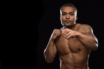 Fototapeta na wymiar Muscular shirtless male fighter on black background