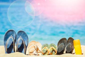 Naklejka premium Stylish beautiful slippers in the sand on the sea background