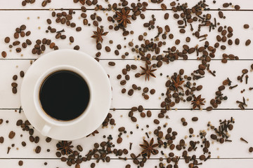 Cup of black coffee on a wooden background with spices and coffee grains. Author processing, film effect.