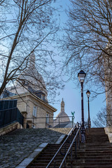 Typical Montmartre staircase with old street lamp and sacre coeur in background in winter. Paris, France