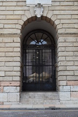 Huge entrance of glass and steel under the arch in stone wall, Catania, Sicily, Italy